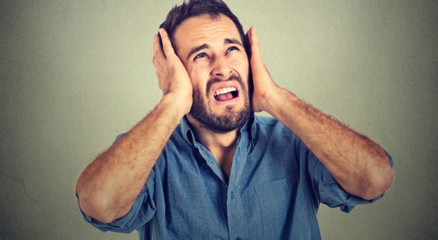 Ringing in My Ears | Calgary Alberta | Soundwave Hearing Care unhappy man blocking out noise with his hands