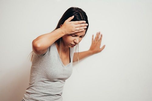 woman wincing holding her forehead