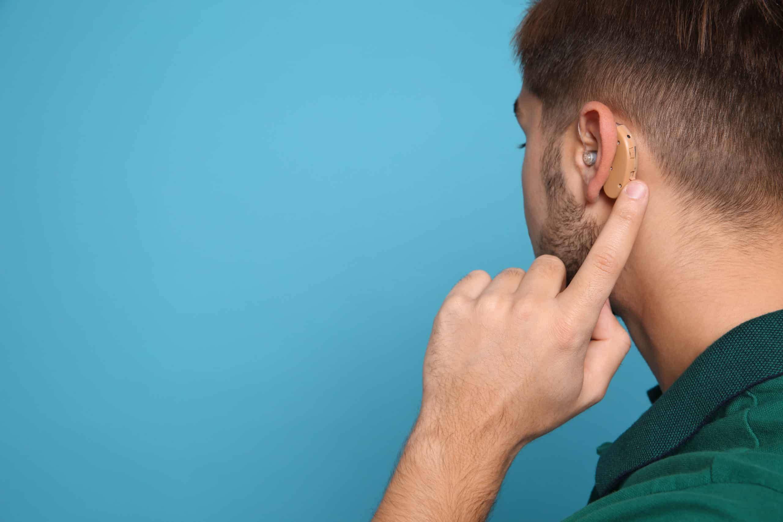 A man pointing to a small heading aid behind his ear A man pointing to a small heading aid behind his ear