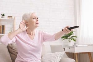 Senior woman cupping her hand behind ear to hear better