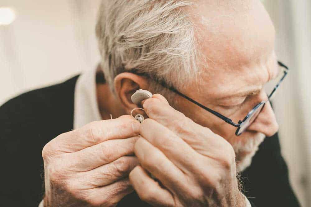 Older man putting his hearing aids on