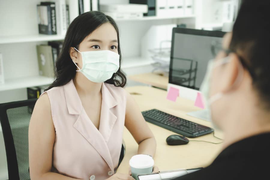 two people having a conversation wearing face masks