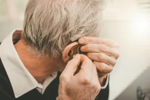 Senior gentleman removing his squeaking hearing aid