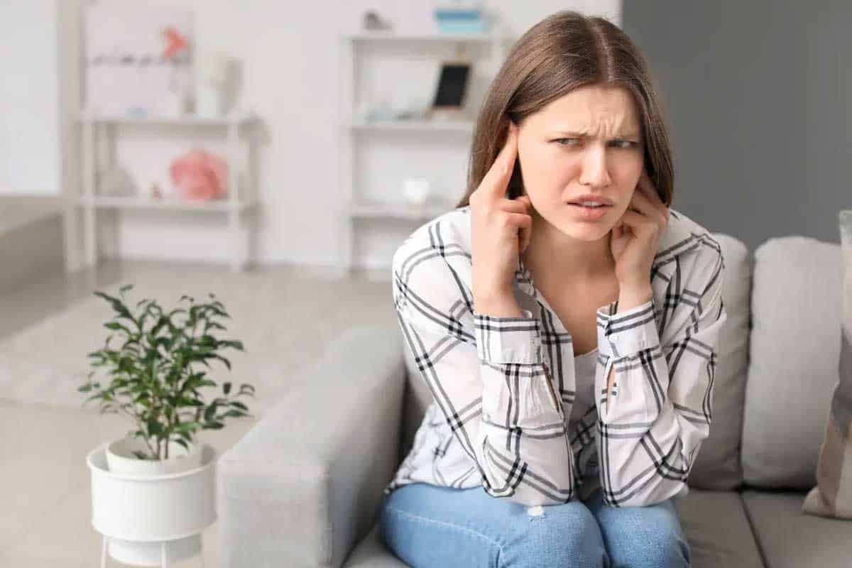  A woman covering her ears due to irritation from sounds