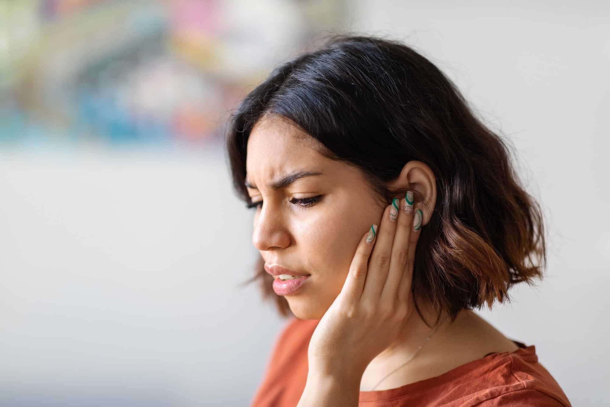 hyperacusis-min a woman holding her ear in deep thought or pain