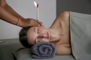 Ear candling: a woman lying down with a candle over her ear