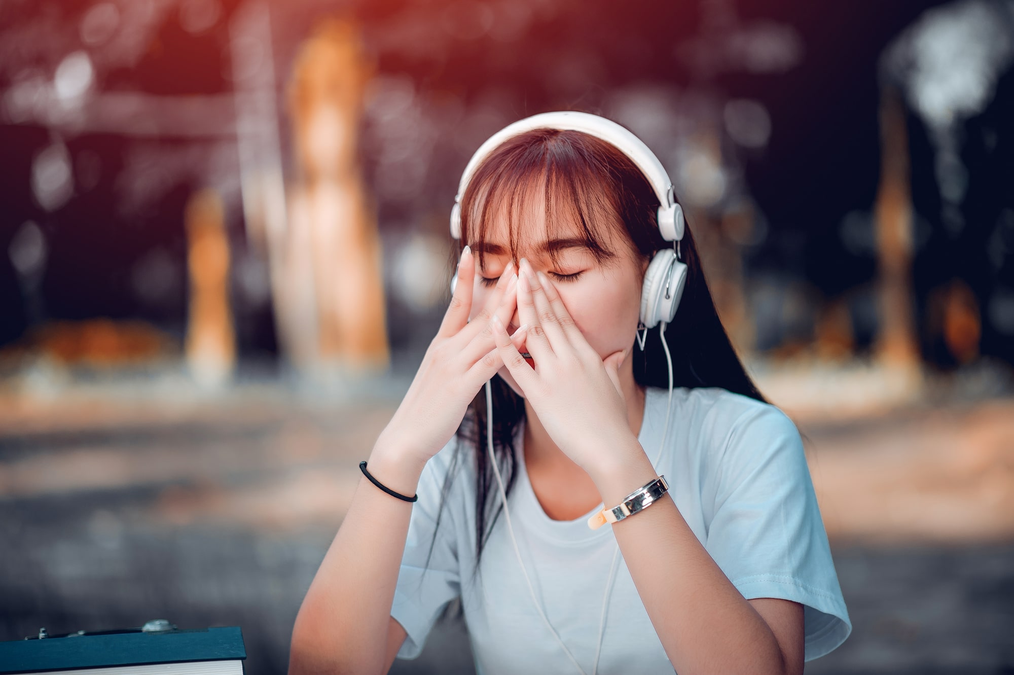 A young woman with headphones covering her face with her hands A young woman with headphones covering her face with her hands