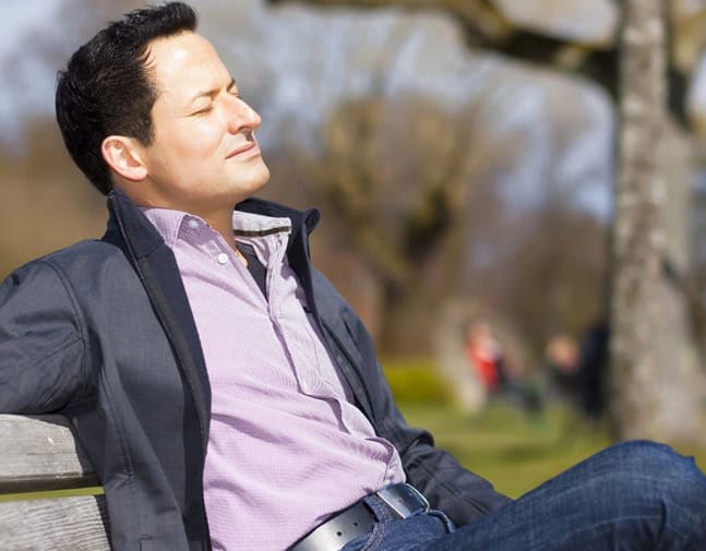 Man sitting on a bench relaxing in a park post img Man sitting on a bench relaxing in a park.