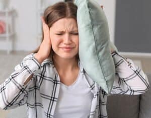 Young woman suffering from loud noise at home