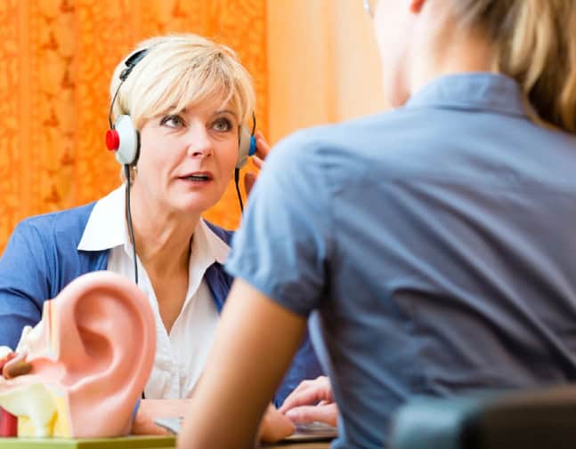 A person wearing headphones during a hearing test with a clinician in a hearing clinic