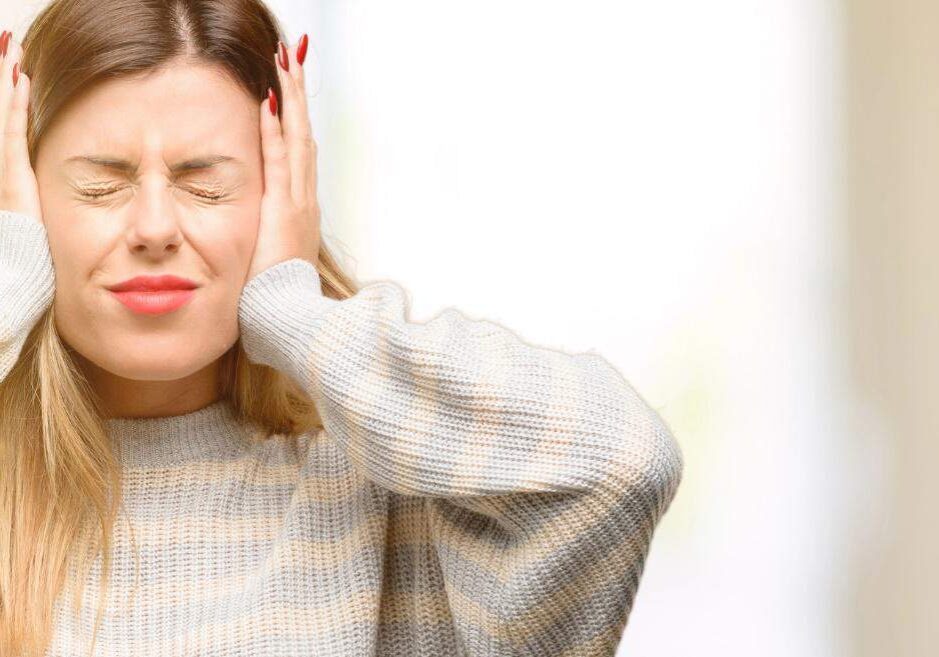 A young woman pressing her ears with her hands