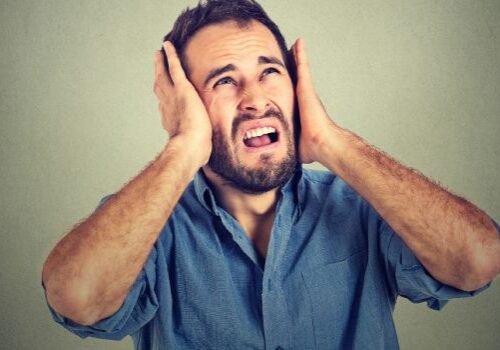 unhappy man blocking out noise with his hands