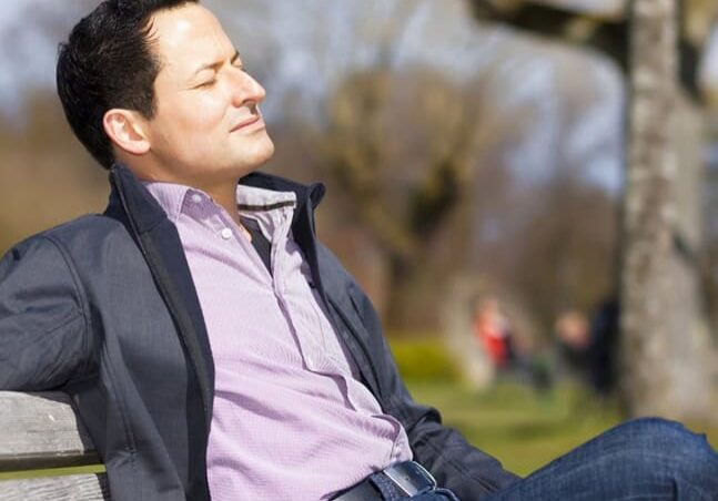 Man sitting on a bench relaxing in a park.