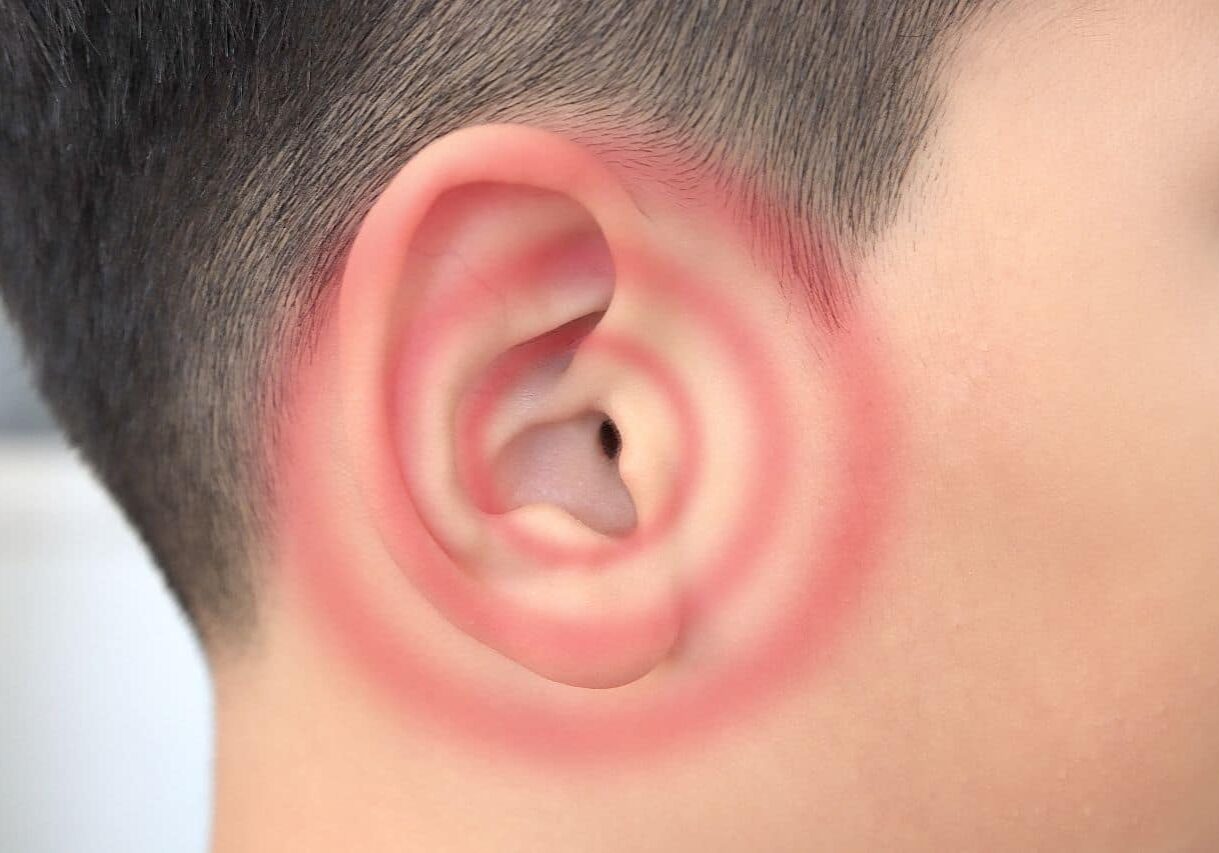 Young boy’s ear close up with red ripples signaling tinnitus