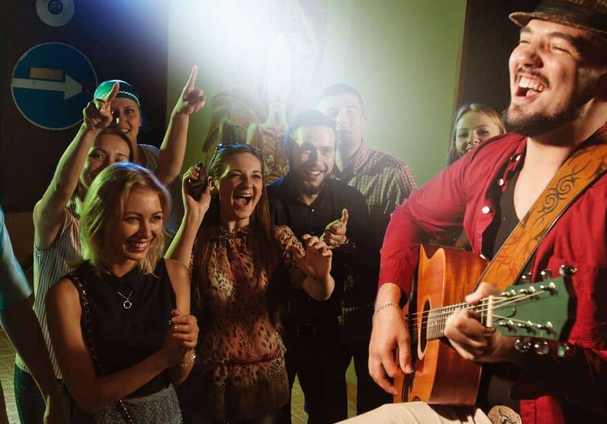 man playing the accoustic guitat in front of their friends