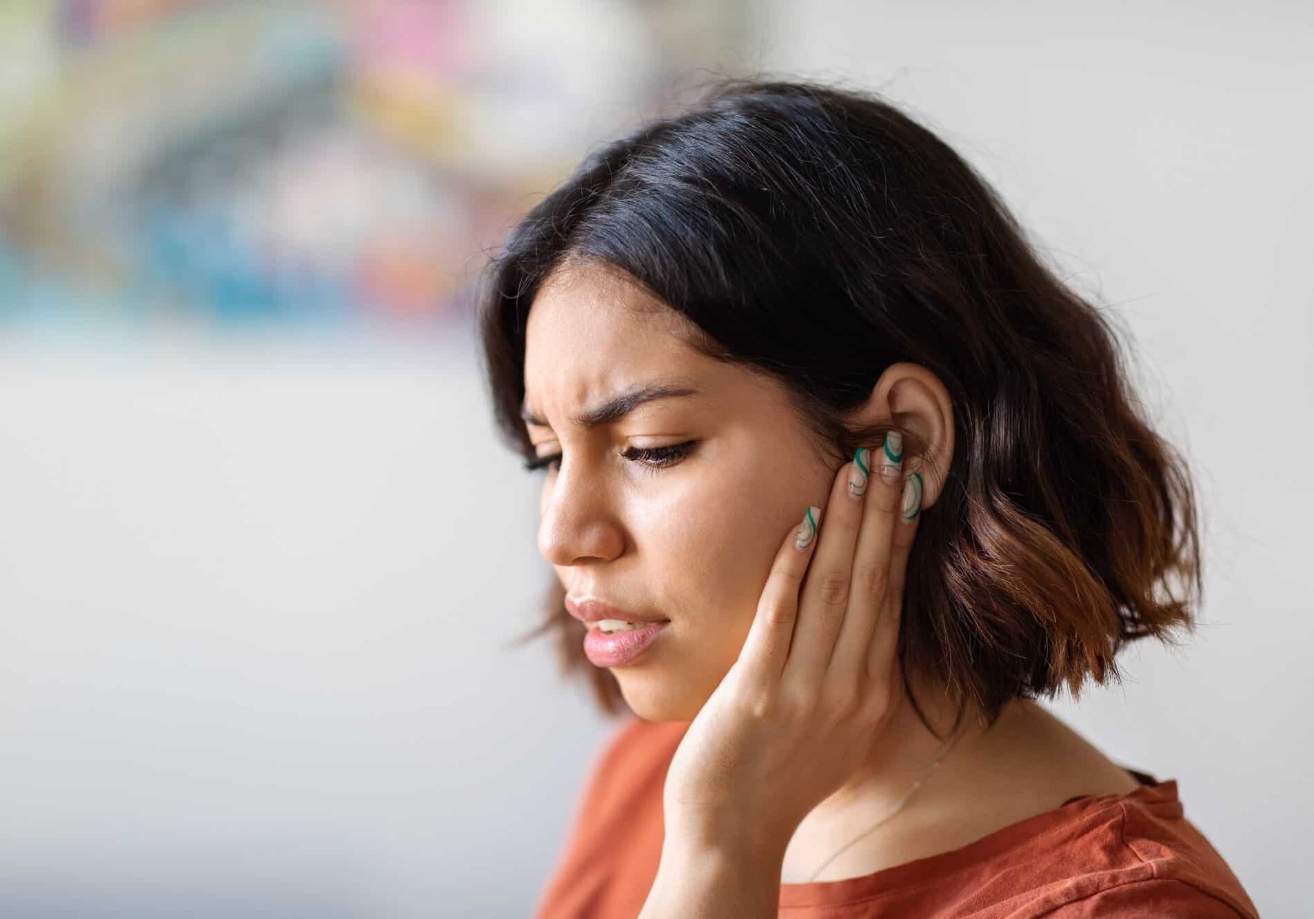 a woman holding her ear in deep thought or pain
