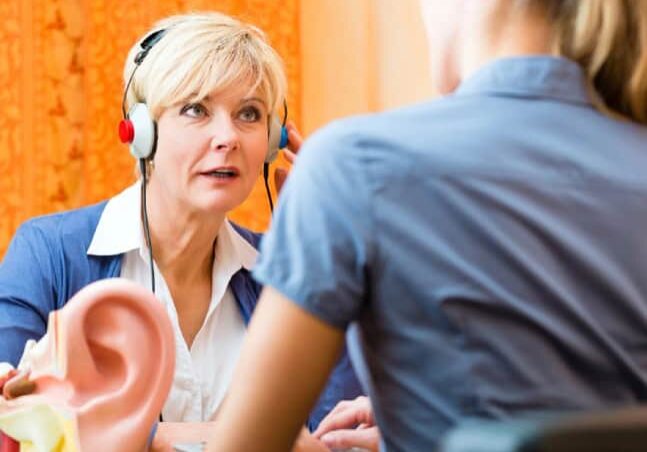 A person wearing headphones during a hearing test with a clinician in a hearing clinic